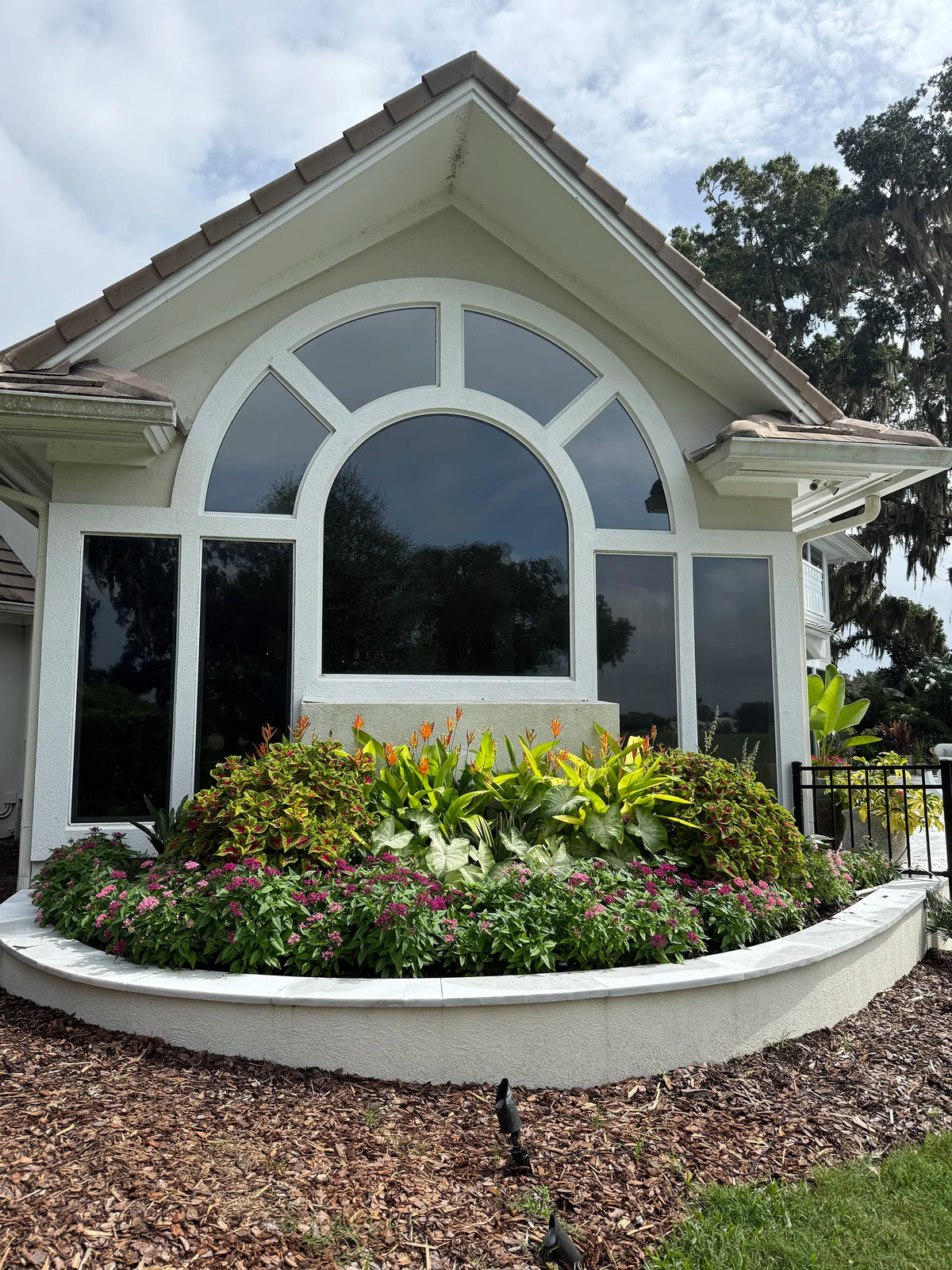 A flower bed outside the window of a home.