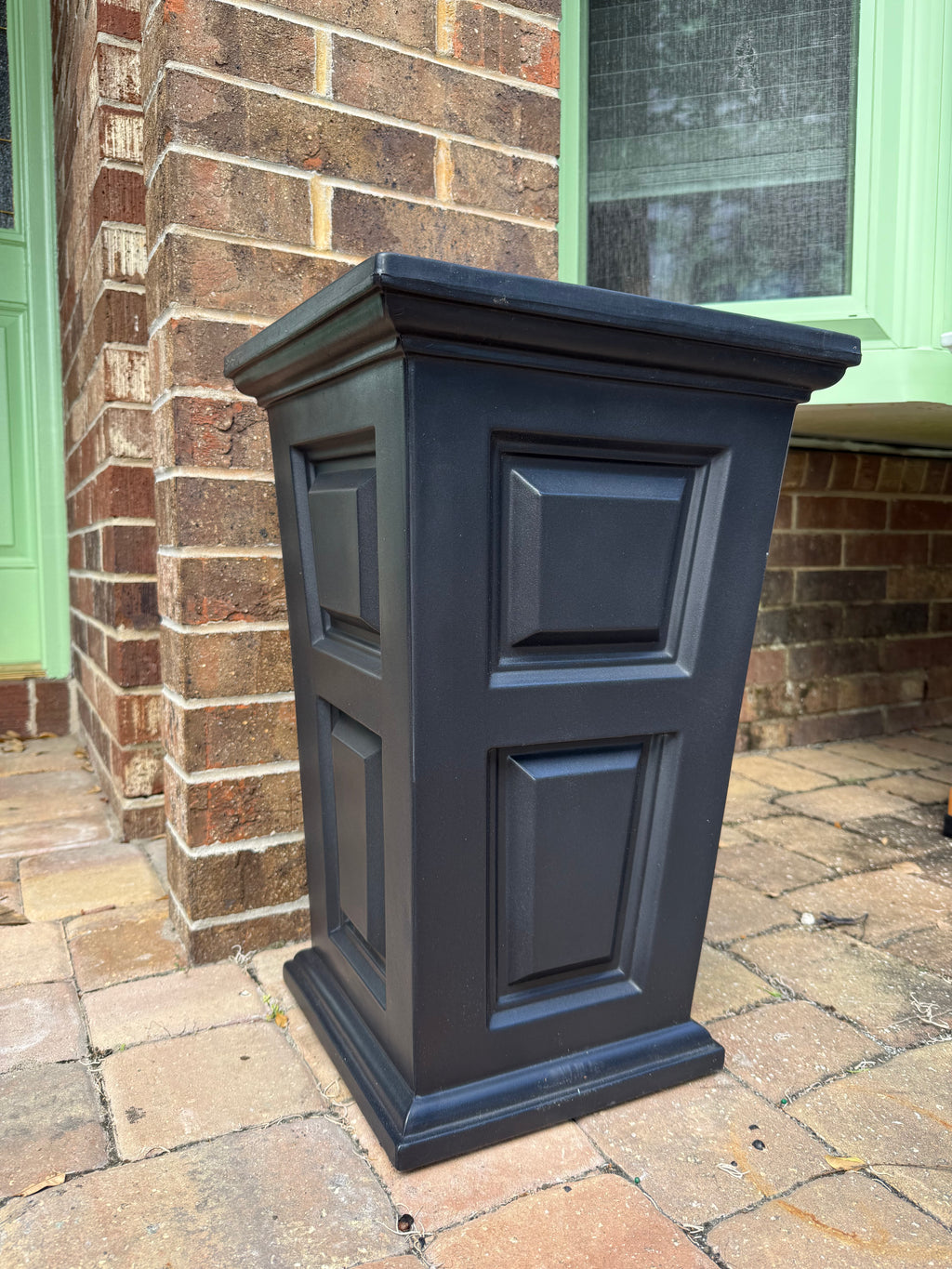 Black decorative planter against a brick wall