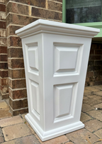 White decorative planter against a brick wall