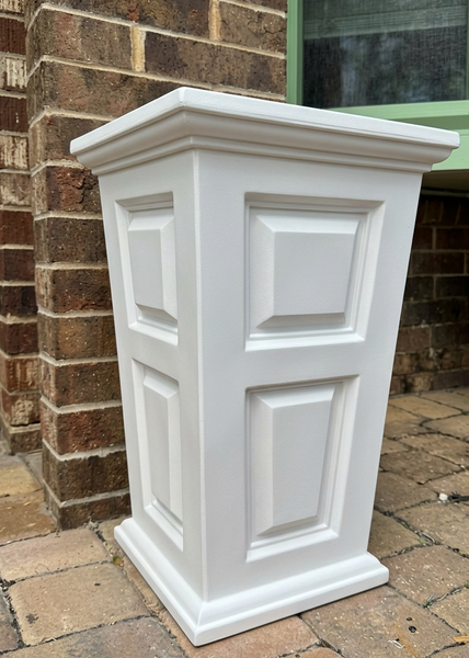 White decorative planter against a brick wall